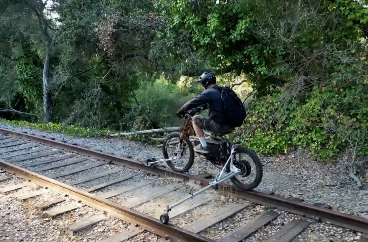 Rider demonstrating a removable rail-guide assembly on an electric bicycle